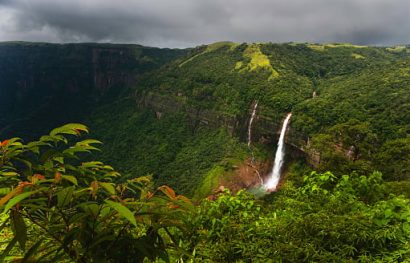 Elevated view across the Khasi hills with view of Nohkalikai waterfalls flanked by deep gorge with forested slopes under overcast sky near Shillong, Meghalaya, India.